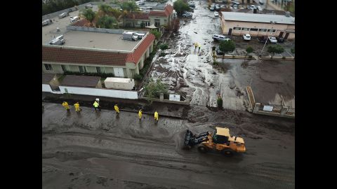 Los Angeles firefighters work amid floodwaters and mud on January 9, 2018.