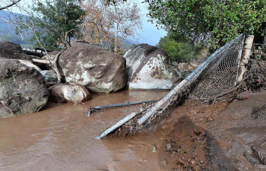 Mudslides pushed boulders near a broken fence in Carpinteria on Tuesday. 