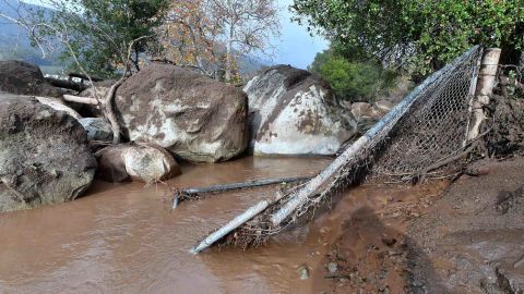 Mudslides pushed boulders near a broken fence in Carpinteria on Tuesday. 