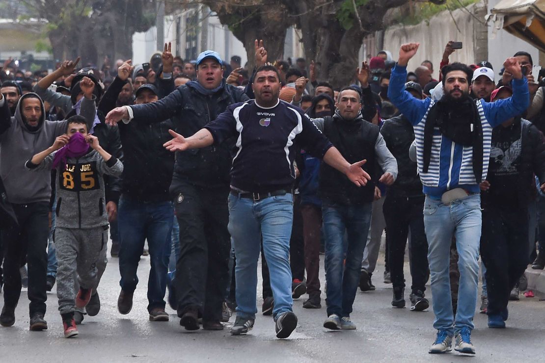 Tunisian protesters gesture toward security forces during clashes in the town of Tebourba on Tuesday following the funeral of a man who died the previous day at an anti-austerity protest.