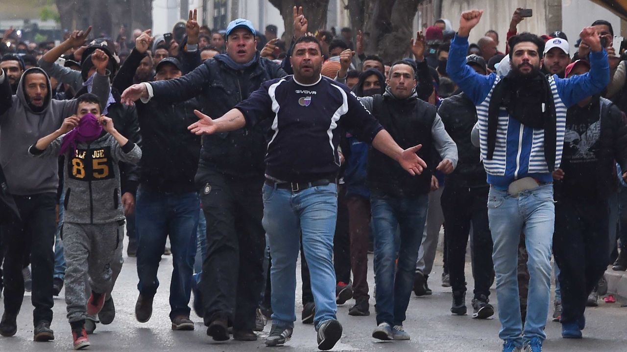 Tunisian protesters gesture toward security forces during clashes in the town of Tebourba on Tuesday following the funeral of a man who died the previous day at an anti-austerity protest.