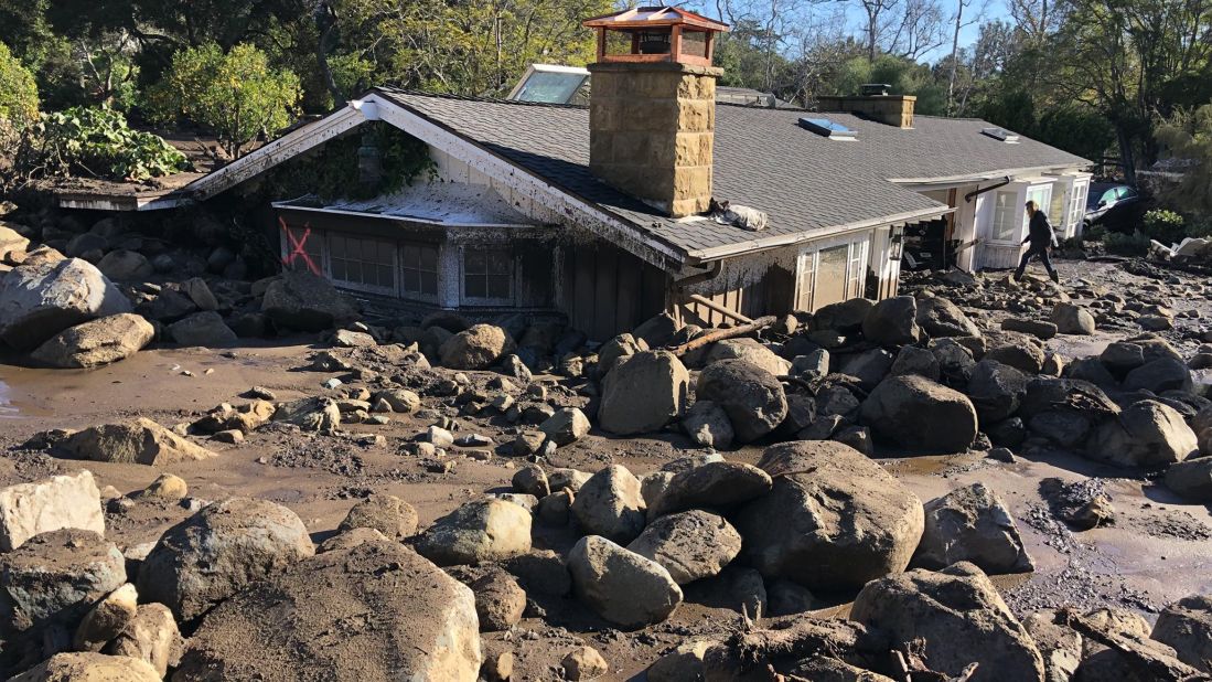 Kerry Mann navigates the large boulders and mudflow that destroyed her friend's home in Montecito.