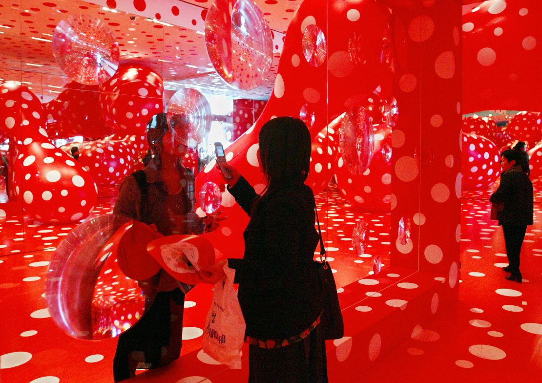 Visitors enjoy "Kusamatrix", which incorporates polka-dot paintings, balloons and mirrors, by Japanese contemporary artist Yayoi Kusama at the Mori Art Museum in Tokyo (2004). 