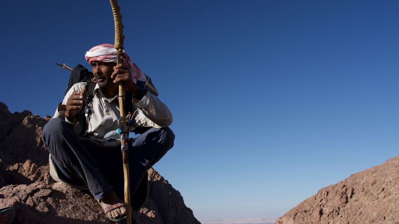 <strong>Sinai's desert leaders: </strong>Jebeleya guide Nasser Mansour rests after the steep climb out of the Blue Desert. Wearing a traditional, red-and-white Bedouin shemagh, or head wrap, his walking stick is topped with the horn from a Nubian ibex, which he found at the edge of the trail.