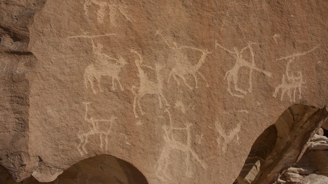 Petroglyphs depicting camels and riders are etched into trailside boulders.
