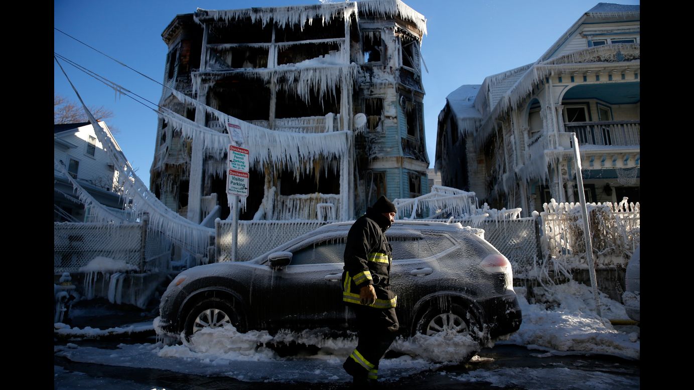 A firefighter walks past a Boston house that caught fire the night before on Saturday, January 6.