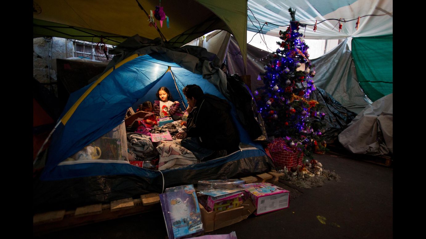 Julio Dominguez Lozara watches his daughter Cynthia and her two sisters play with Three Kings Day gifts in a Mexico City tent camp on Saturday, January 6. They have been living in the tent camp since their apartment was damaged in a <a href="http://www.cnn.com/interactive/2017/09/world/mexico-quake-cnnphotos/" target="_blank">September earthquake.</a>