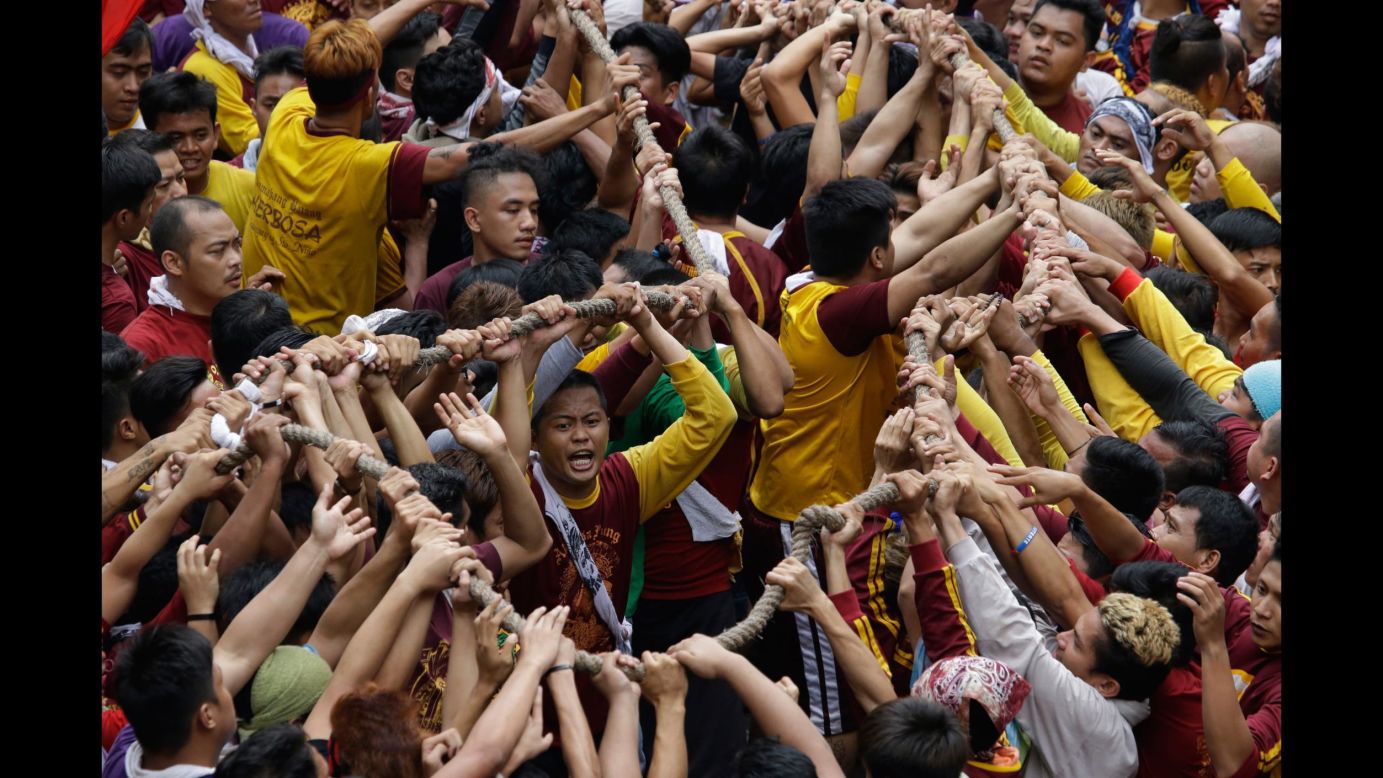 Roman Catholics grab a rope, pulling a carriage with an image of the Black Nazarene, during a procession in Manila, Philippines, on Tuesday, January 9.