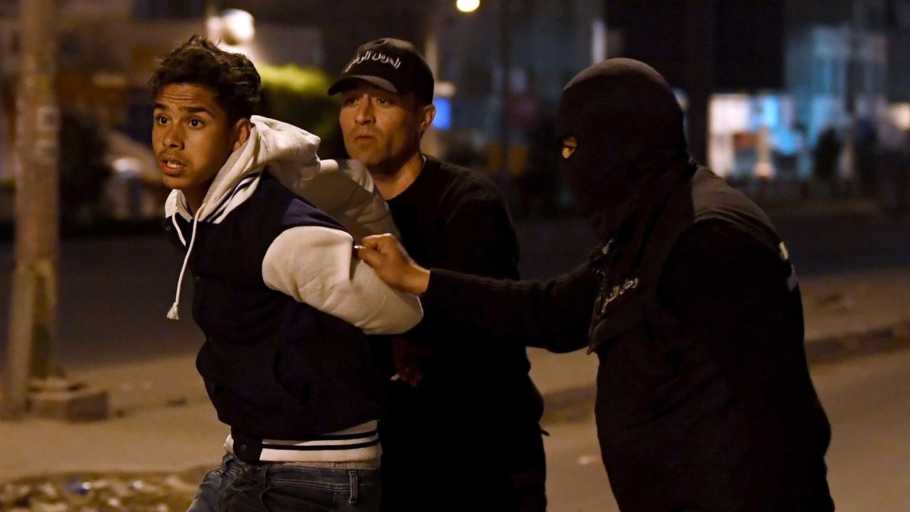 Tunisian security forces detain a protester late Wednesday on the outskirts of the capital, Tunis.