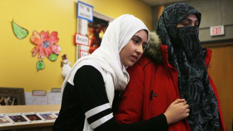 Khawlah Noman, 11, hugs her mother,  Saina Samad, after talking to reporters Friday in Toronto.