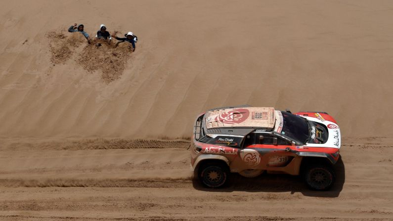 Spectators lie in the sand as Sheikh Khalid Al Qassimi of United Arab Emirates and his co-driver, Xavier Panseri of France, compete during Stage 8 of the 2018 Dakar Rally between Uyuni and Tupiza, Bolivia, on Sunday, January 14.