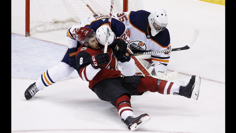 Arizona Coyotes right wing Tobias Rieder, No. 8, gets shoved to the ice by Edmonton Oilers defenseman Darnell Nurse, No. 25, as Oilers goaltender Al Montoya, No. 35 makes a save on Friday, January 12.<br />