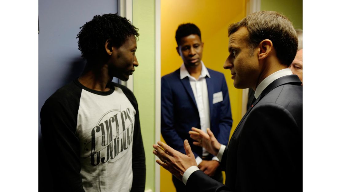 French President Emmanuel Macron talks to Ahmed Adam, left, from Sudan during his visit to a migrant center in Croisilles, northern France.