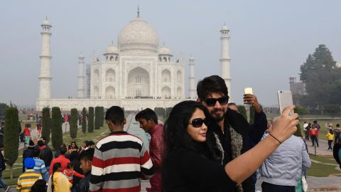 Tourists take selfies against the backdrop of the Taj Mahal.