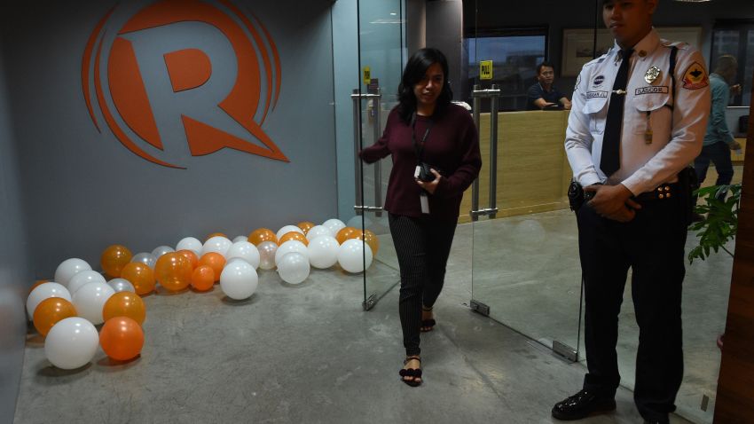An employee (L) of online portal Rappler heads out from their editorial office in Manila on January 15, 2018, while a private security guard stands. 
The Philippine government has revoked the operating licence of leading news website Rappler, officials said January 15 in a ruling denounced by President Rodrigo Duterte's critics as another blow to press freedom. / AFP PHOTO / TED ALJIBE        (Photo credit should read TED ALJIBE/AFP/Getty Images)