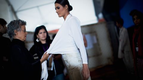 Pakistani designer Maheen Khan makes fiinishing touches on a model wearing one of her creations during Fashion Pakistan Week in November 2009 in Karachi.