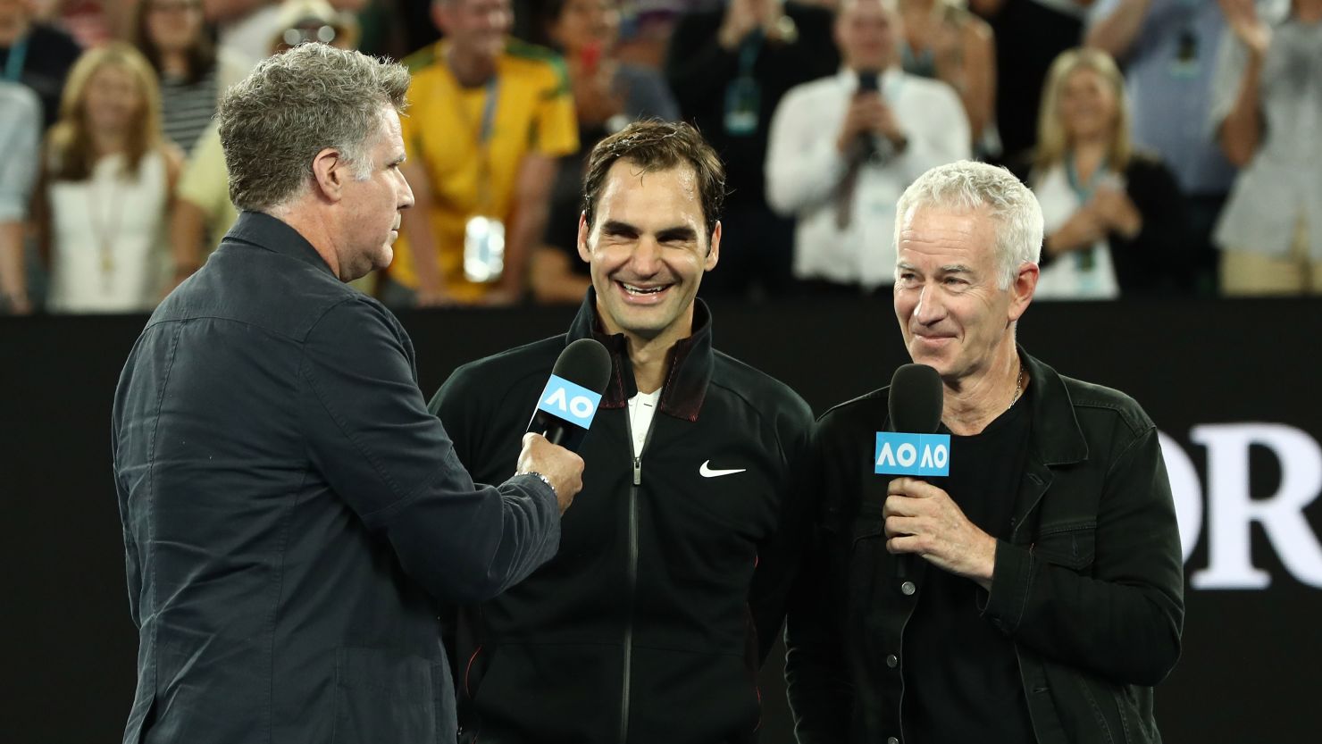 MELBOURNE, AUSTRALIA - JANUARY 16:  Will Ferrell (L) and John McEnroe (R) interview Roger Federer of Switzerland after Federer won his first round match against Aljaz Bedene of Slovenia on day two of the 2018 Australian Open at Melbourne Park on January 16, 2018 in Melbourne, Australia.  (Photo by Ryan Pierse/Getty Images)