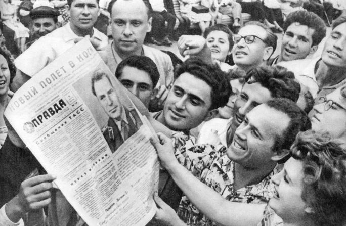 People in the streets are shown looking at the same newspaper.