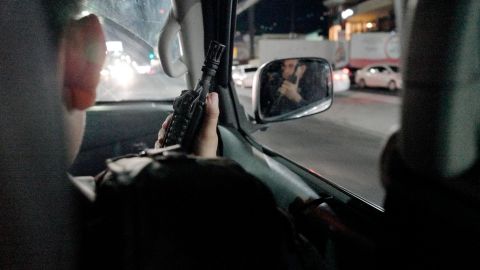 While on patrol, a member El Salvador's National Civil Police points his assault rifle out the car window. Police say gang members often possess more fire power than they do.