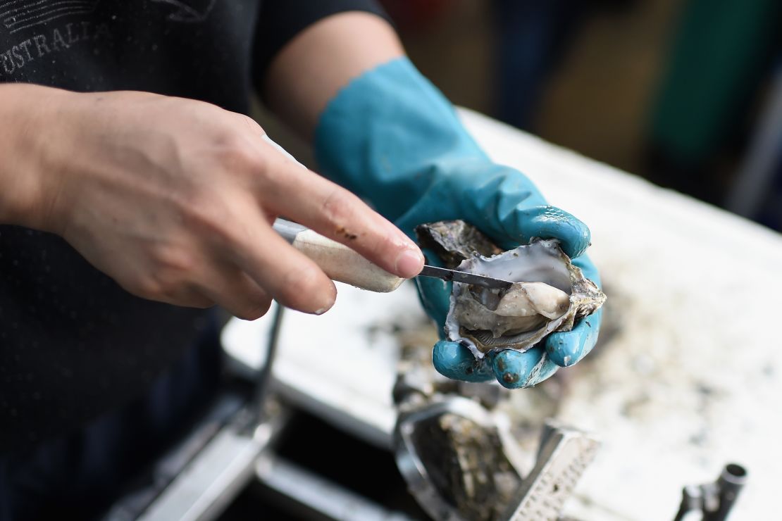 A fishmonger shucks an oyster at the Sydney Fish Market.