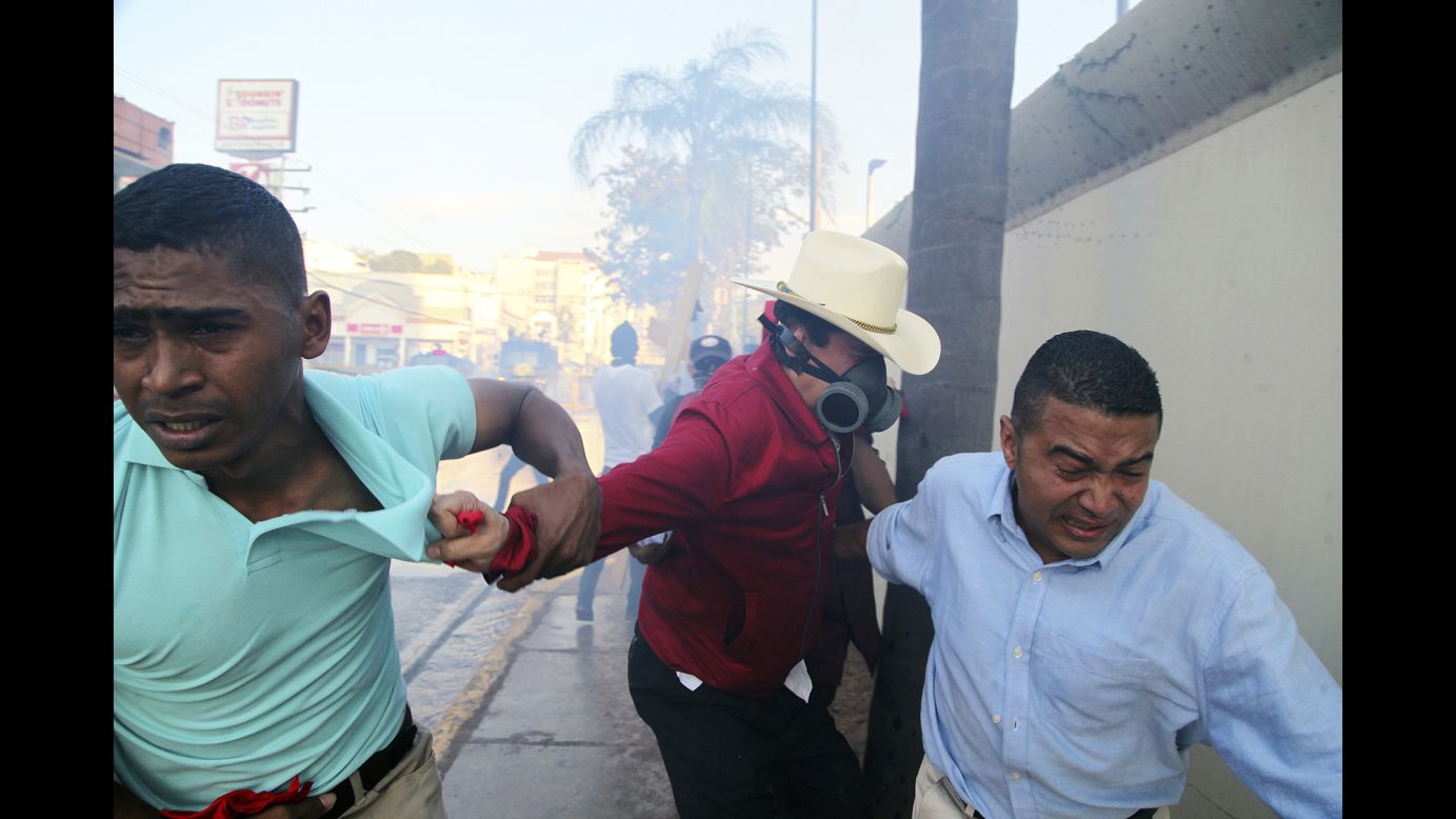 Former Honduran President Jose Manuel Zelaya is pulled to safety after military police threw tear gas during a protest near the Presidential House in Tegucigalpa, Honduras, on Friday, January 12.