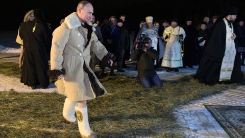 Putin wore a thick coat and boats before stripping off to take the plunge.
