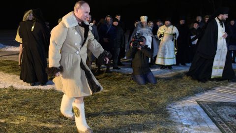 Putin wore a thick coat and boats before stripping off to take the plunge.