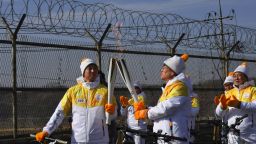 Torchbearers 'kiss' with their torches to pass the Olympic flame in front of a military fence on the road leading to the border truce village of Panmunjom during the PyeongChang 2018 Torch Relay in Paju on January 19, 2018.
North and South Korea have agreed to march together under a single flag at the Winter Olympics opening ceremony, in the latest sign that the crisis on the peninsula may be easing. / AFP PHOTO / JUNG Yeon-Je        (Photo credit should read JUNG YEON-JE/AFP/Getty Images)