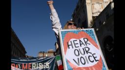 A woman lifts her fist while holding a banner during a Women's March demonstration in Rome on Saturday.