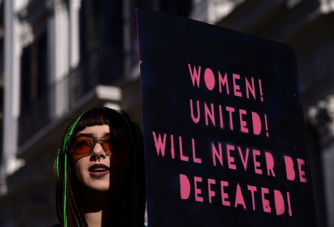 A woman holds a sign reading "Women united! Will never be defeated!" during a demonstration in downtown Rome.