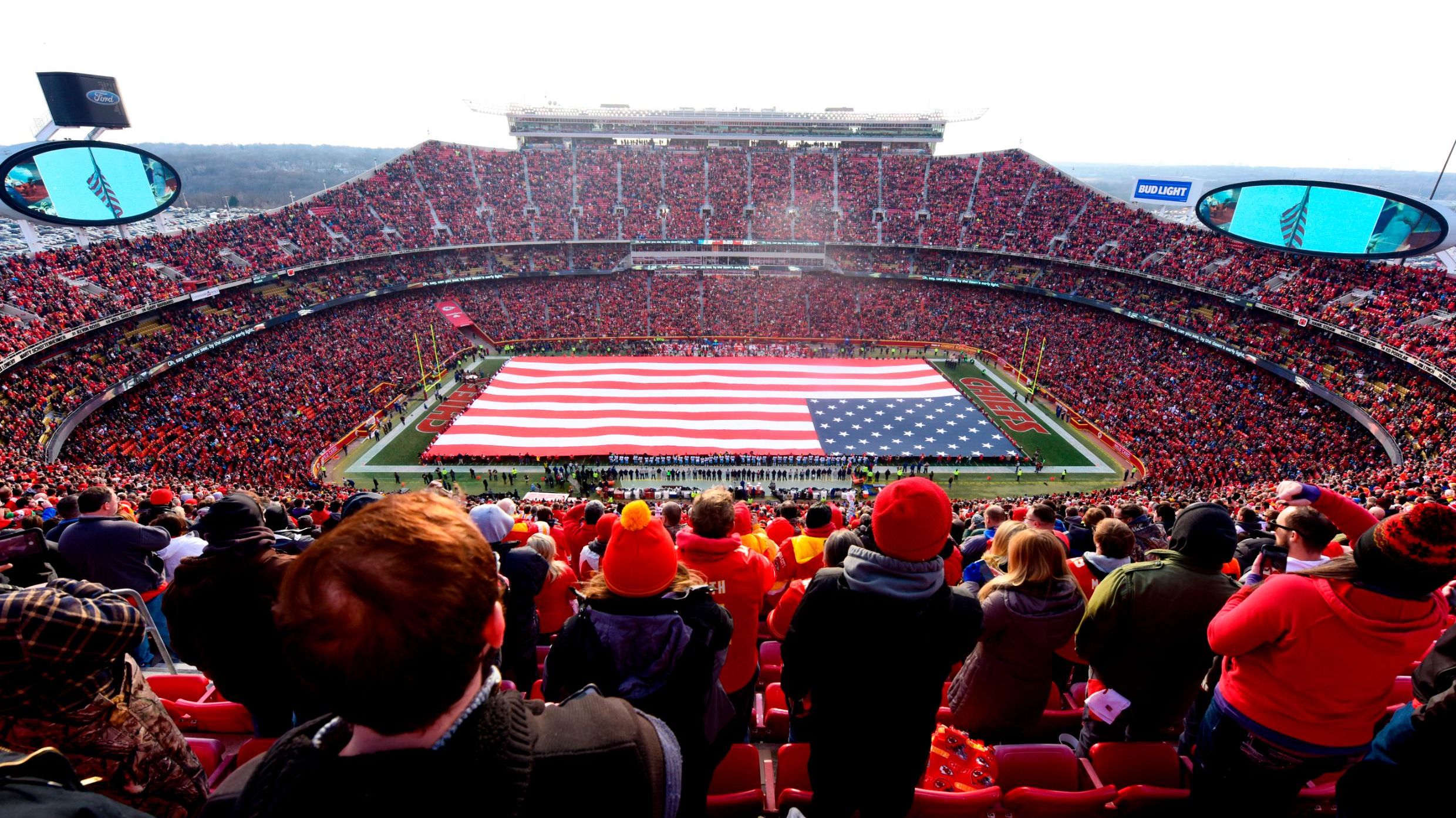 Fans stand at attention for the national anthem overlooking a 100 yard American flag prior the AFC Wild Card Playoff Game between the Kansas City Chiefs and the Tennessee Titans at Arrowhead Stadium on January 6, 2018 in Kansas City, Missouri.