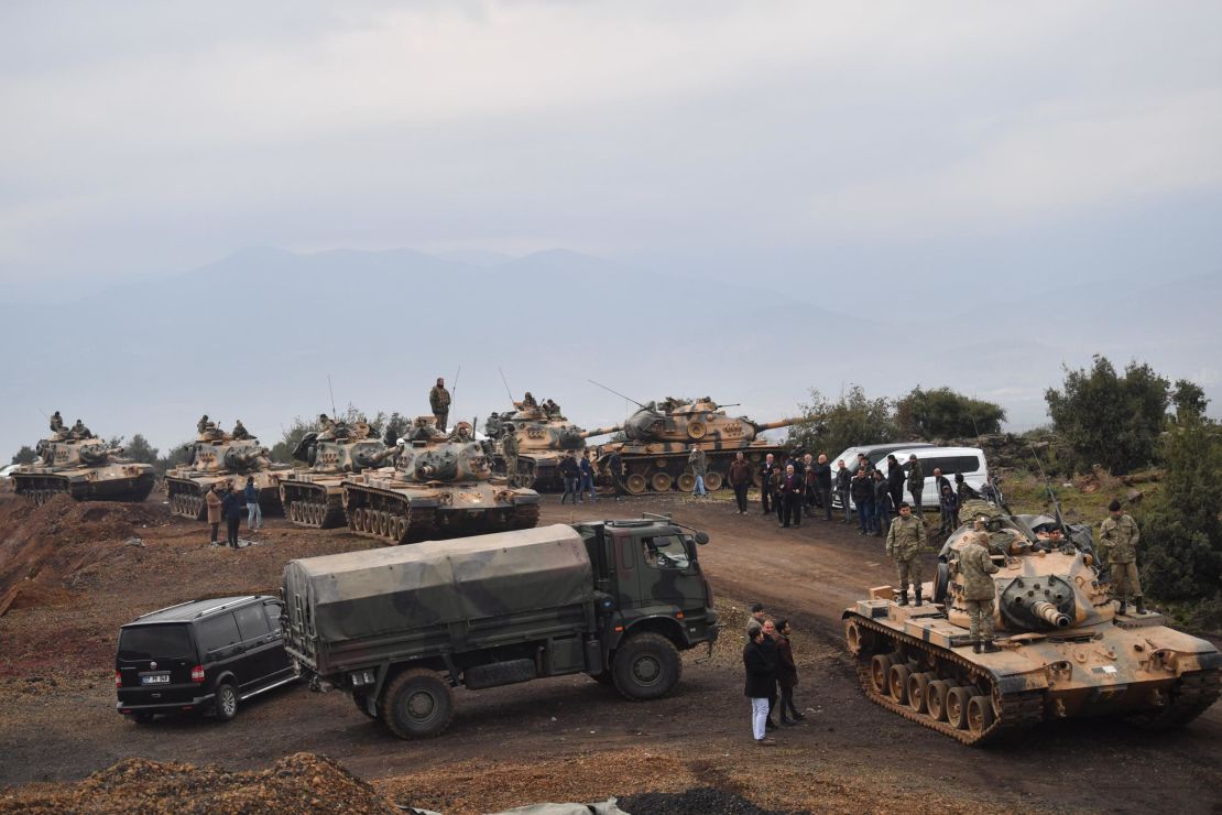 Villagers watch as Turkish army tanks and soldiers gather near the Syrian border on January 21.