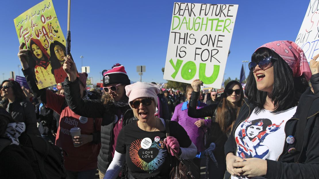 Protesters carry signs as they make their way to Sam Boyd Stadium for the Women's March "Power to the Polls" voter registration tour launch on Sunday in Las Vegas. 