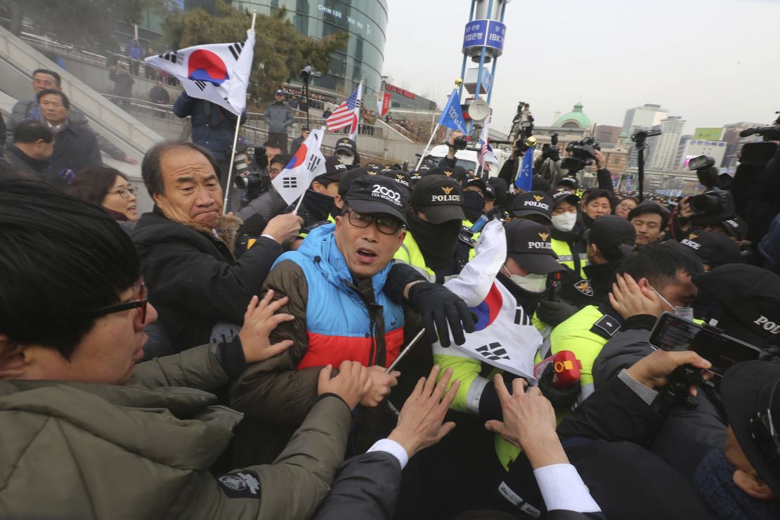 South Korean protesters struggle with police officers as police use fire extinguishers during a rally Monday.