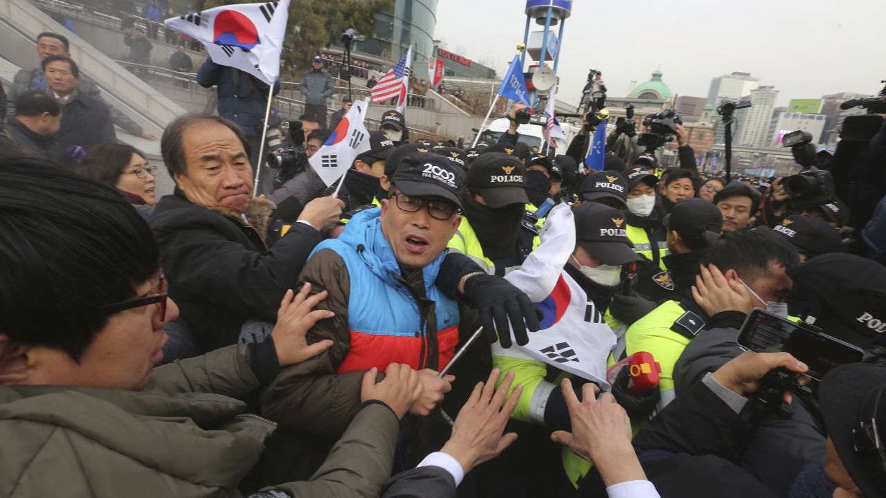 South Korean protesters struggle with police officers as police use fire extinguishers during a rally Monday.