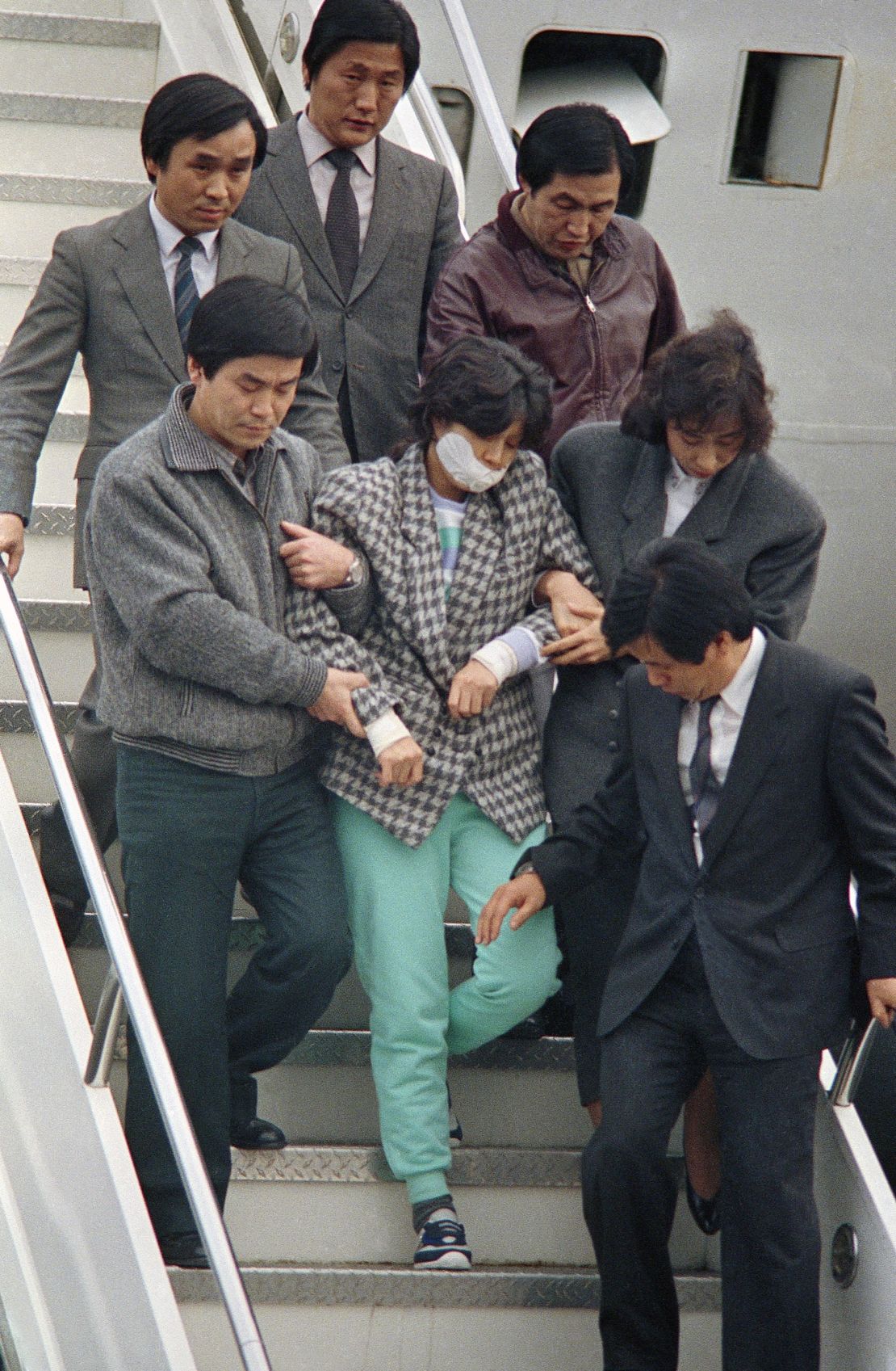 Agents escort Kim Hyon Hui, with her mouth taped shut, as she arrives in Seoul, South Korea, Dec. 15, 1987, from Bahrain. 