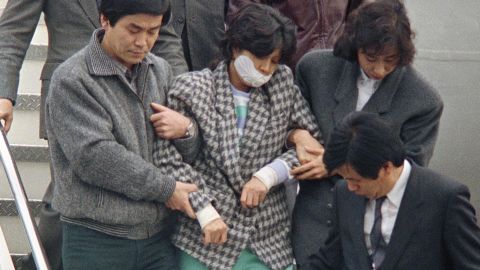 Agents escort Kim Hyon Hui, with her mouth taped shut, as she arrives in Seoul, South Korea, Dec. 15, 1987, from Bahrain.