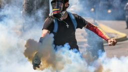 A demonstrator throws a tear gas canister back at the riot police during clashes in Caracas on January 22, 2018 which erupted during a protest to condemn the death of dissident former police officer Oscar Perez - gunned down in a bloody police operation on February 16. 
Perez, whose body was buried by the government on January 21 against his family's wishes, was Venezuela's most wanted man since June when he flew a stolen police helicopter over Caracas dropping grenades on the Supreme Court and opening fire on the Interior Ministry.  / AFP PHOTO / Juan BARRETO        (Photo credit should read JUAN BARRETO/AFP/Getty Images)