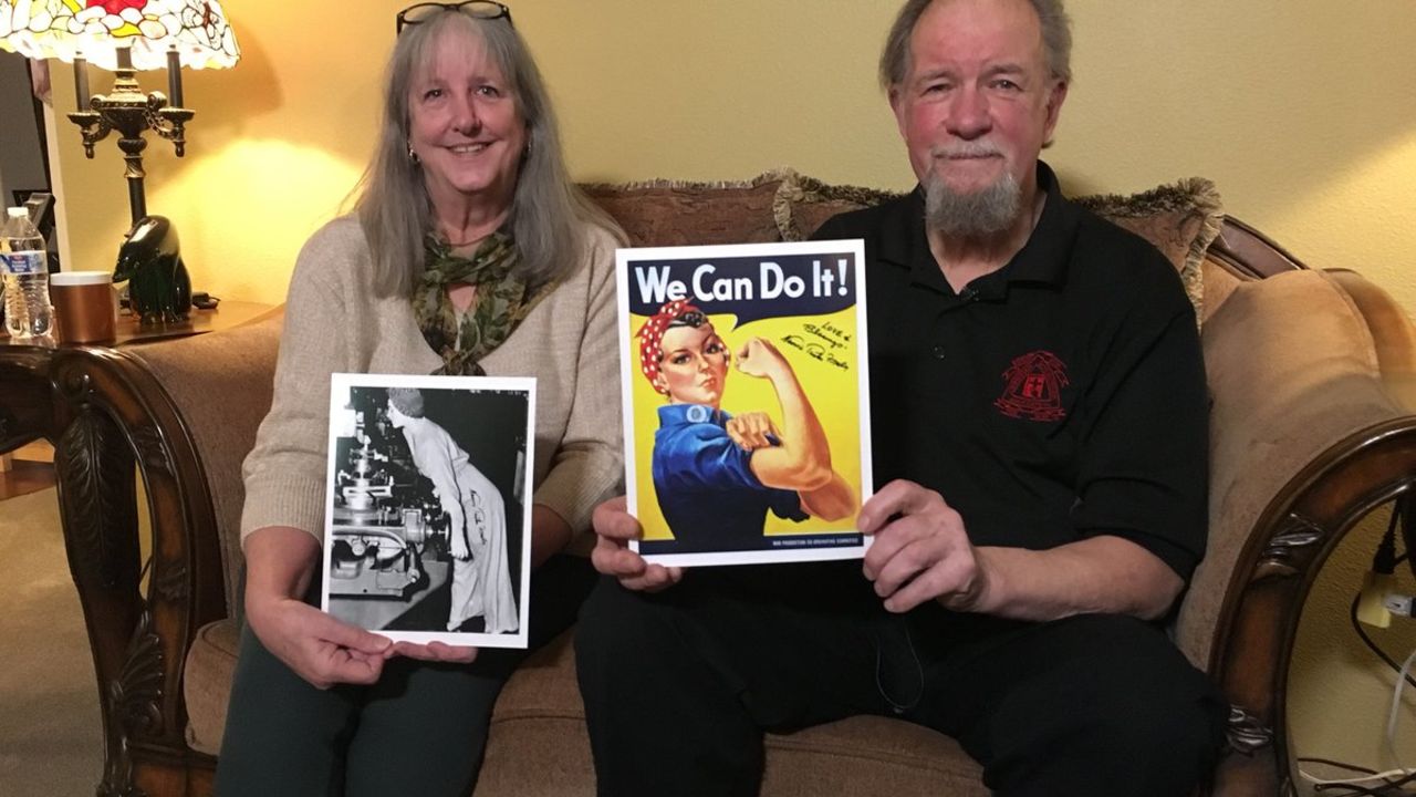 Naomi Parker Fraley's daughter-in-law and son hold up a photograph of her taken during World War II and the poster it inspired.