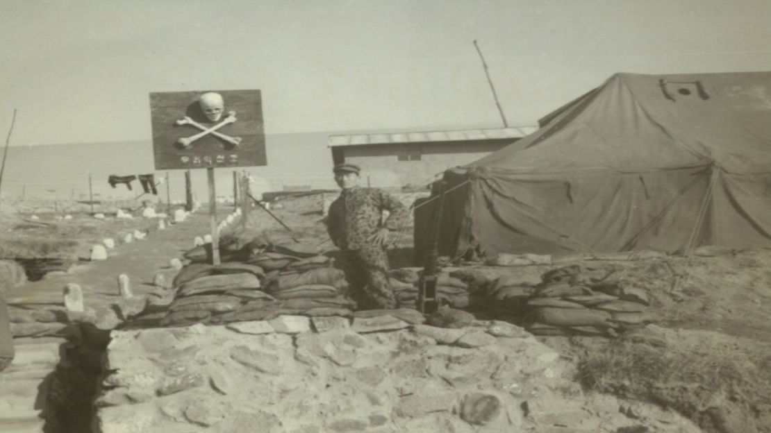 A photo from 1970 shows Air Force Sergeant Yang Dong-soo standing in front of a skull and crossbones sign on the island of Silmido. Yang was assigned to train members of the assassination squad when he was 21 years old. He says the skull and cross bones were real human bones. 