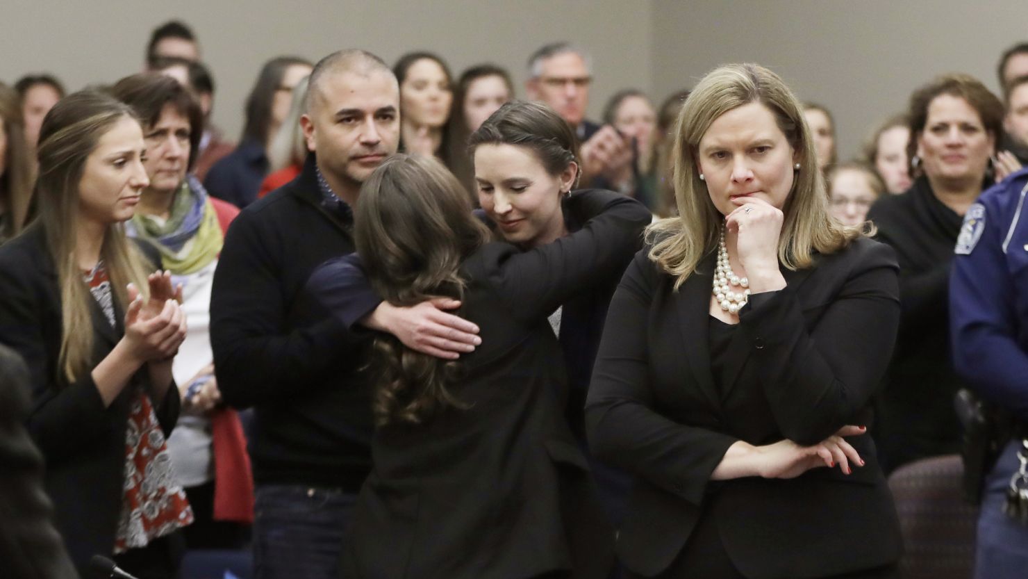 Assistant Attorney General Angela Povilaitis stands in court after former gymnast Rachael Denhollander, center, is hugged following her victim impact statement in the Larry Nassar sentencing proceedings.