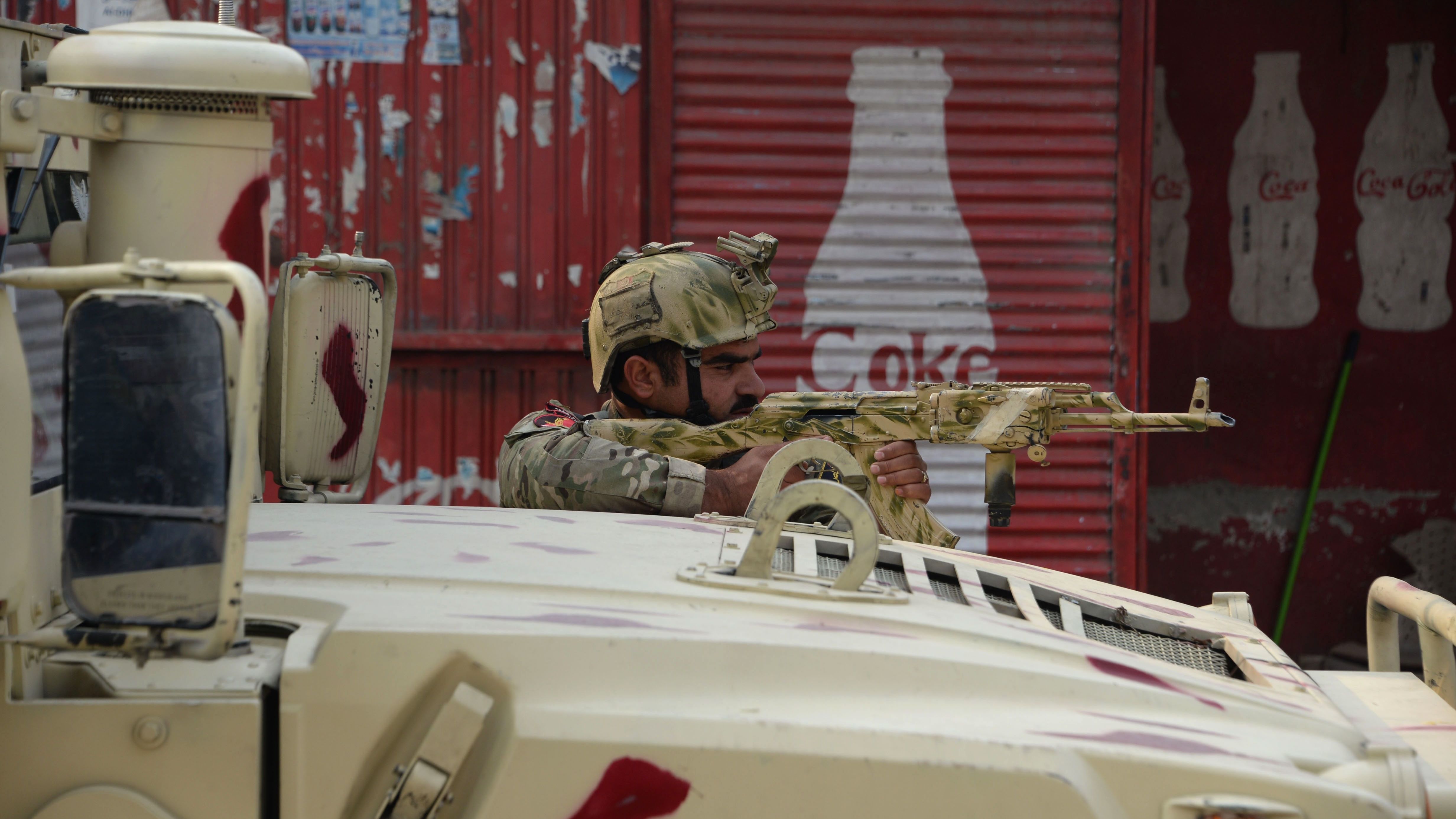 An Afghan army soldier takes a position Wednesday near the Save the Children office in Jalalabad. 