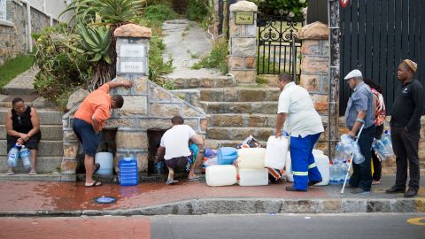 People collect water from pipes fed by an underground spring in St. James, a Cape Town suburb. 