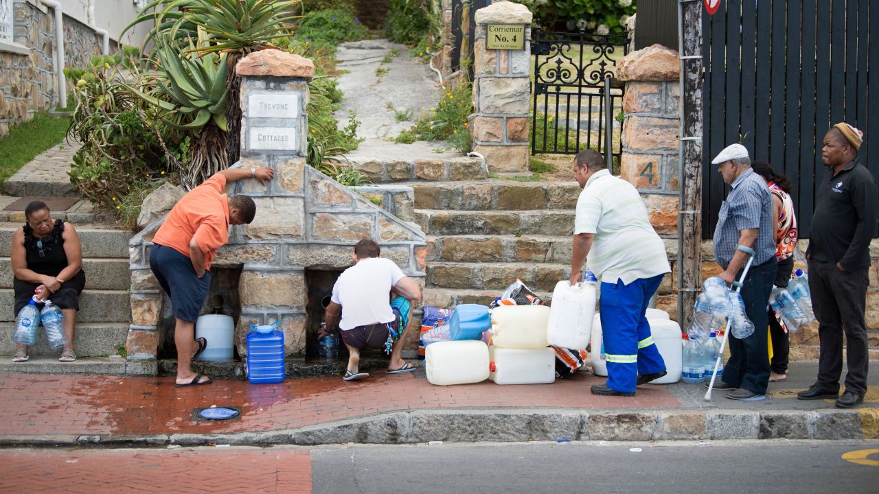 People collect water from pipes fed by an underground spring in St. James, a Cape Town suburb.