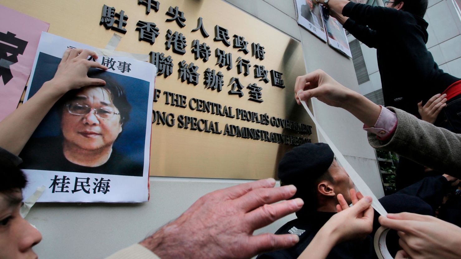 Protesters stick photos of missing publisher Gui Minhai on the outside of a Chinese government building in Hong Kong in July 2016. Gui first disappeared in 2015.