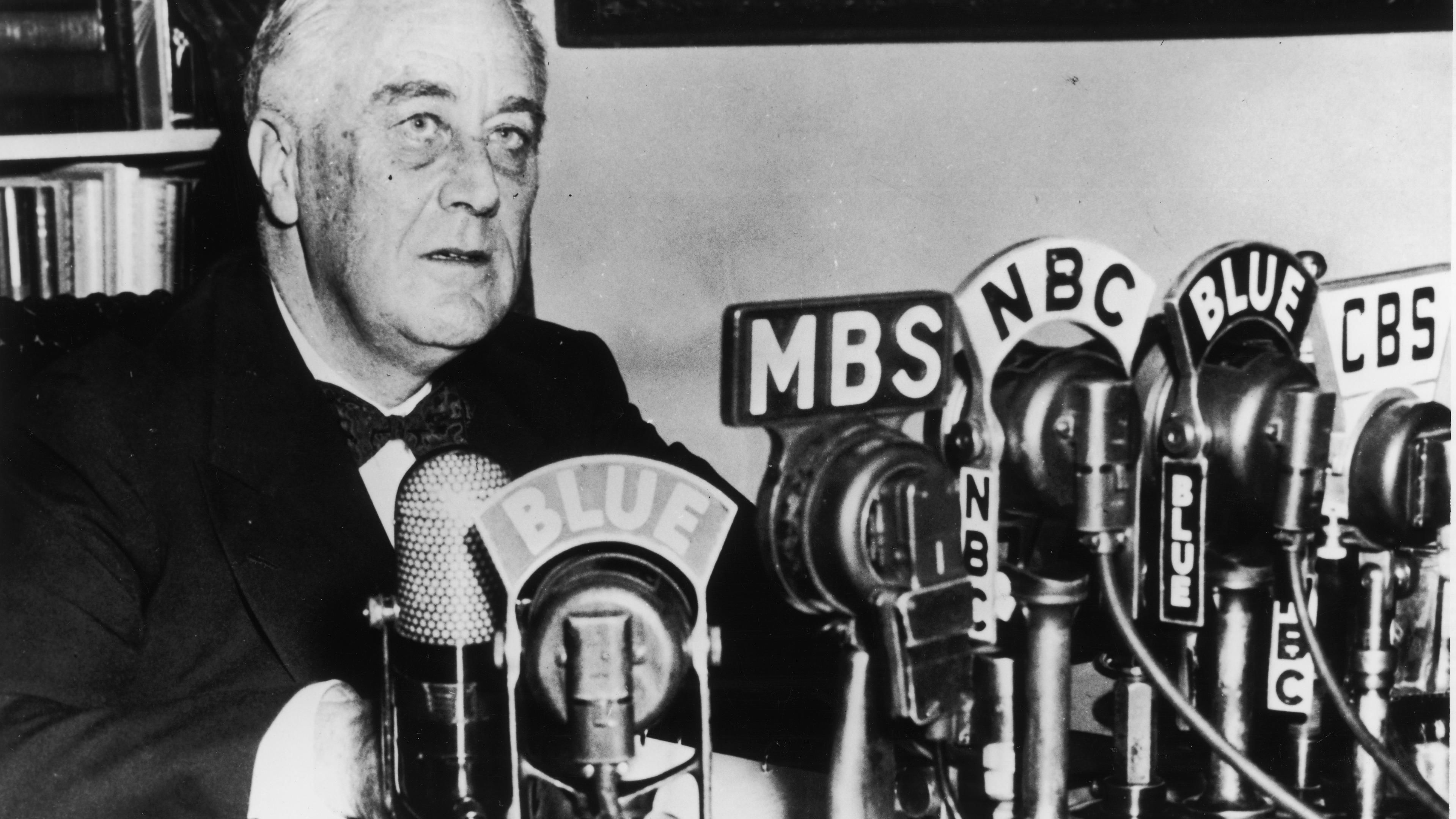 President Franklin D. Roosevelt seated in front of a number of television and radio station microphones, circa 1940s. 