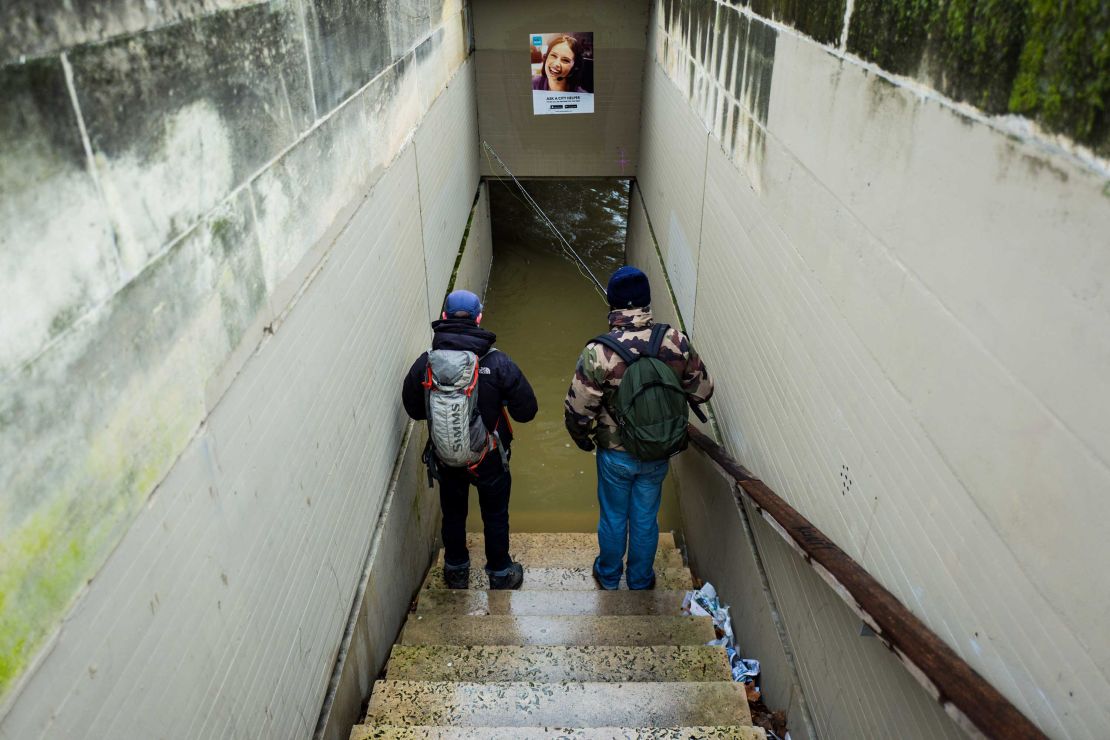 A man, pictured above, takes a photo of the Seine on Friday, days after the river burst its banks causing nearby docks, pictured below, to be completely submerged.