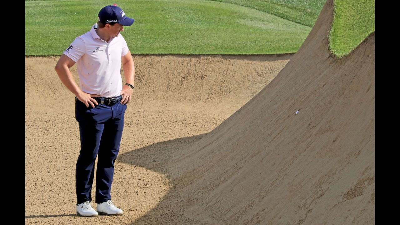 Paul Dunne looks at his ball, which was plugged deep in the face of a greenside bunker during the Omega Dubai Desert Classic on Friday, January 26. 