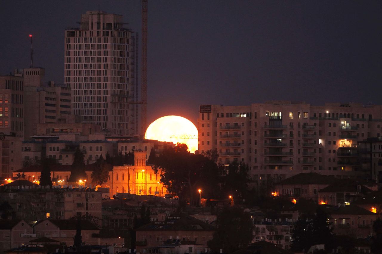 The supermoon sets behind buildings in Jerusalem.