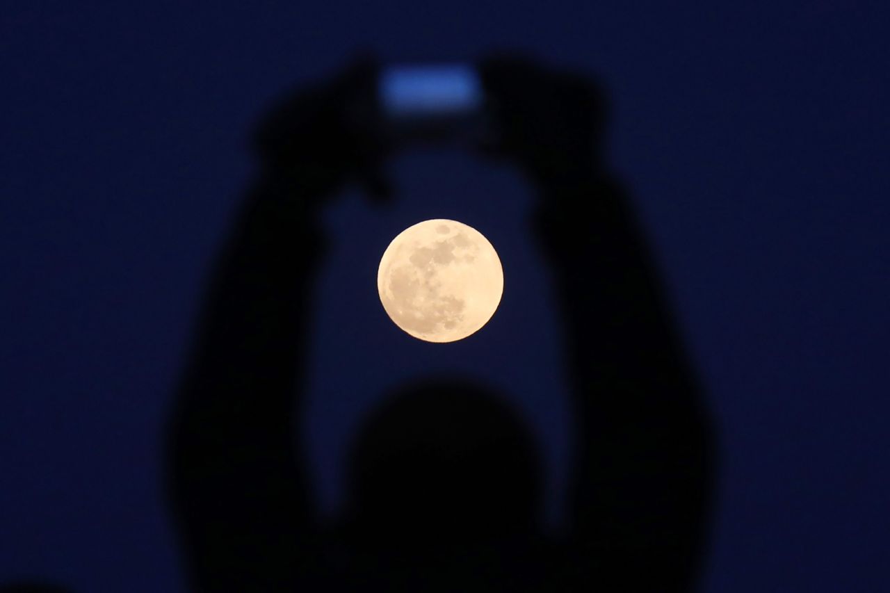 A man takes a photo of the supermoon rising in Beijing.